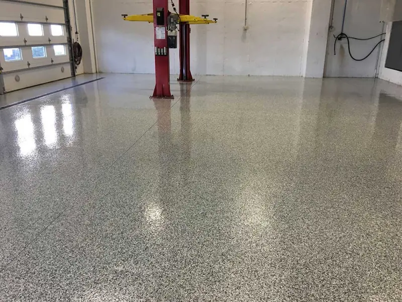 Full-chip epoxy floor coating in a commercial garage with a car lift