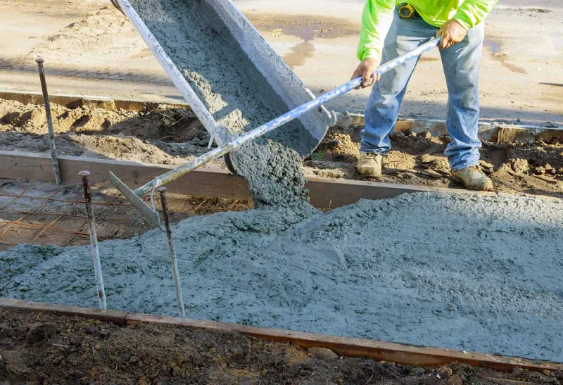 Concrete worker smoothing a fresh slab with a bull float