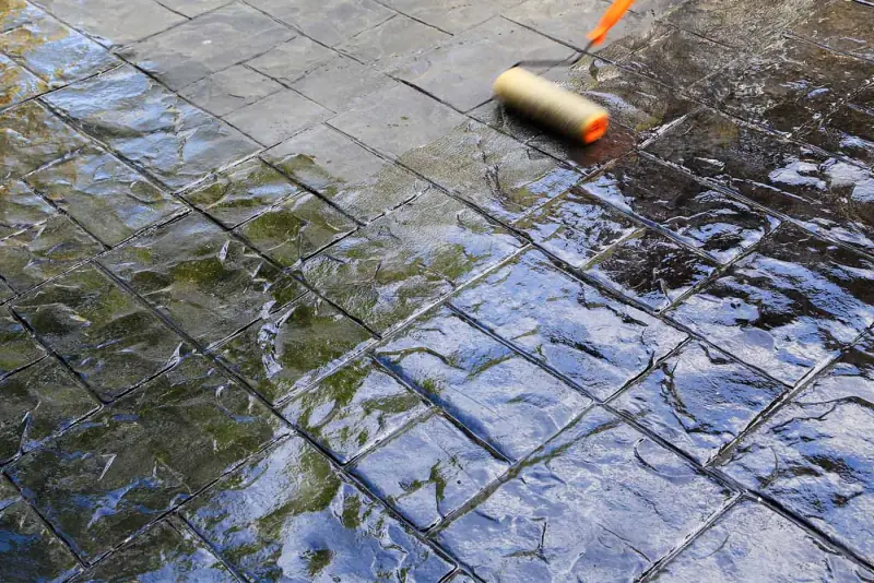 Rolling a glossy sealer onto a stamped concrete surface
